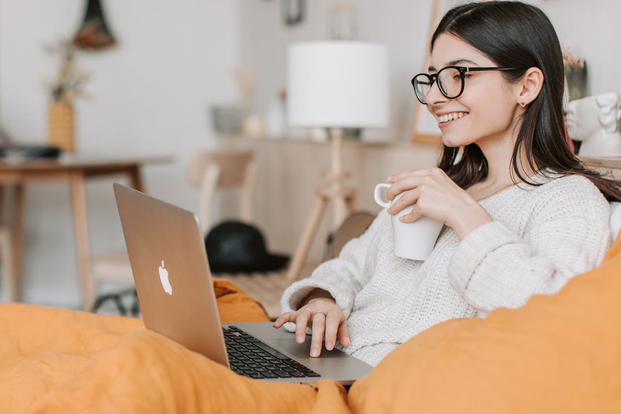 Services Woman enjoying a cozy moment with a laptop and coffee in a modern interior setting.